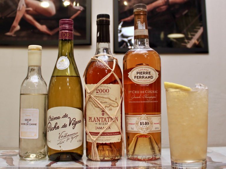 Un Fish House Punch et ses ingrédients principaux, rhum, cognac, crème de pêche et sirop