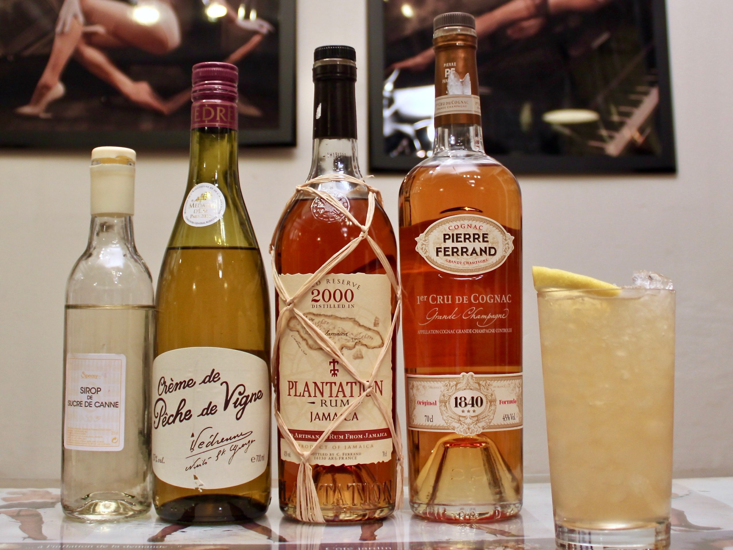 Un Fish House Punch et ses ingrédients principaux, rhum, cognac, crème de pêche et sirop