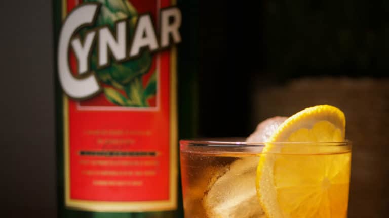 Un Cynar Spritz avec la bouteille de Cynar en fond