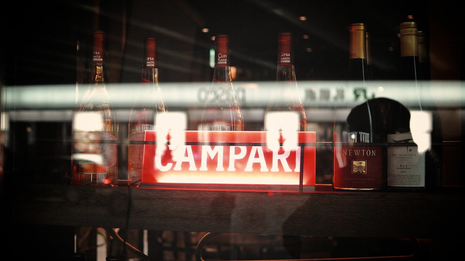 Une enseigne Campari reflétée dans une vitrine