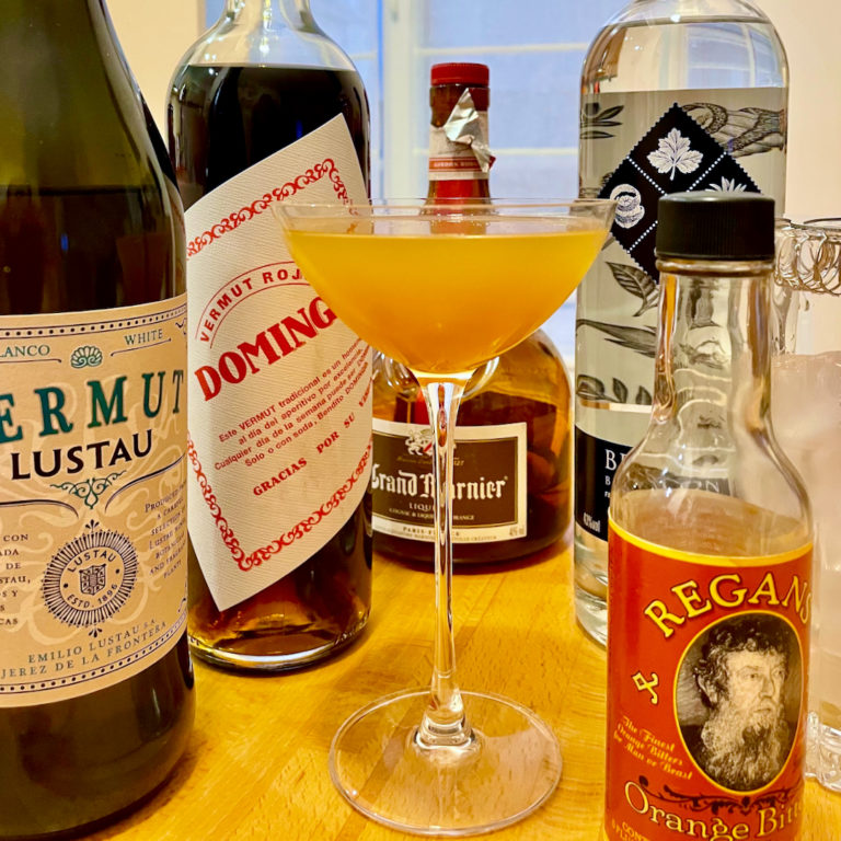 Un cocktail Satan's Whiskers, entouré de ses ingrédients